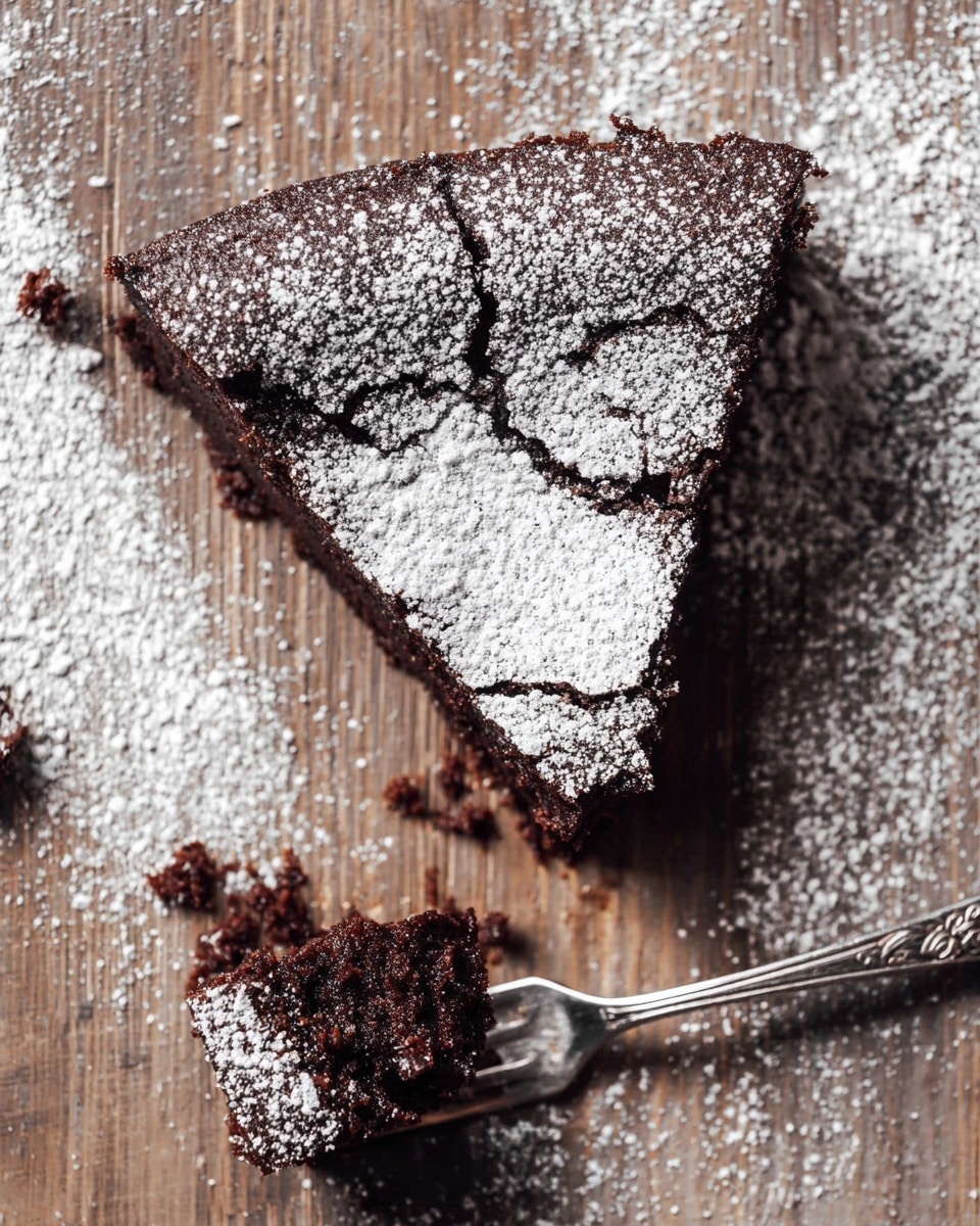 A single piece of dark chocolate cake is shown from above, with a thick top layer dusted unevenly with white powdered sugar, creating a cracked texture on the surface; the cake piece is placed on a wooden board with some scattered powdered sugar and cake crumbs around it. Near the cake, a silver fork with an ornate handle holds a small bite-sized piece of cake, also dusted with powdered sugar. The whole scene has a rustic feel against the wooden background which is replaced with a white marbled texture. photo taken with an iphone --ar 4:5 --v 7