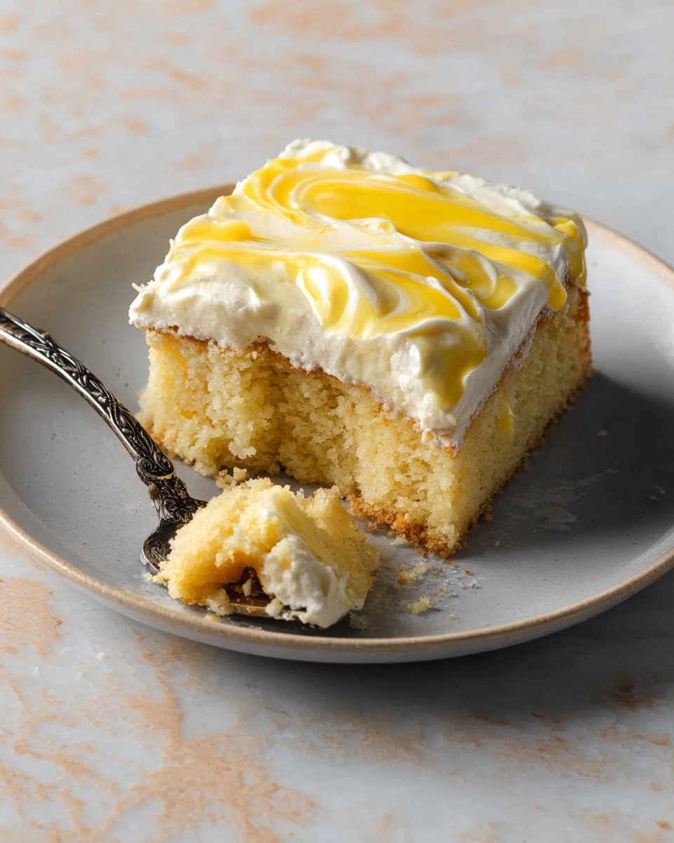 A square slice of yellow cake with a soft crumb base sits on a white plate, topped with a thick, creamy white layer of frosting. The top has swirls of bright yellow sauce or glaze running over the frosting. Next to the cake is a small bitten piece on an ornate silver fork, showing the moist texture of the cake and the creamy frosting. The white plate rests on a white marbled surface. photo taken with an iphone --ar 4:5 --v 7