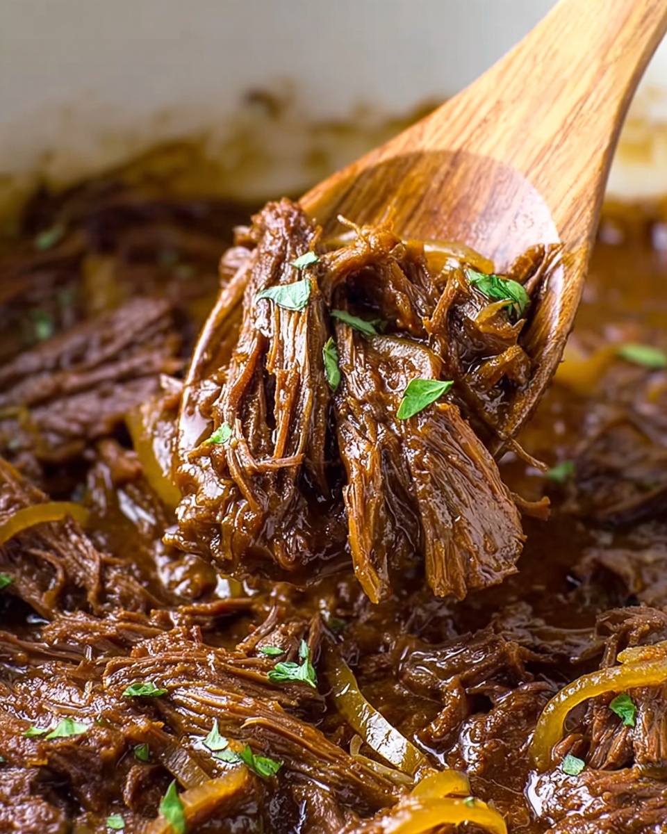 A close-up of shredded beef cooked in a rich brown sauce with soft, thinly sliced yellow onions mixed in. The beef strands are tender and juicy, with small green herb leaves scattered on top for garnish. The wooden spoon lifting the meat shows the texture and moisture clearly, with the background showing more of the same shredded beef and sauce. The setting is on a white marbled surface. photo taken with an iphone --ar 4:5 --v 7