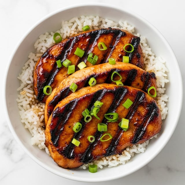 A white bowl filled with three thick slices of grilled chicken glazed with shiny, dark brown sauce, placed on top of a layer of fluffy white rice. The chicken has a slightly charred texture with visible grill marks. Bright green chopped scallions are sprinkled over the chicken and sauce, adding a fresh touch. The bowl is set on a white marbled surface. photo taken with an iphone --ar 4:5 --v 7