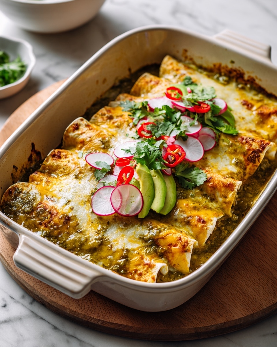 A white baking dish holds three rolled enchiladas covered in melted light yellow cheese and green sauce, with some cheese browned and crispy on the edges. On top, there are thin, round slices of red and white radishes scattered along with small diced red peppers and fresh green cilantro leaves. A dollop of smooth green guacamole sits near one corner, adding a creamy texture contrast. In the background, there is a blurred wooden bowl with red and green limes, all set on a white marbled surface. photo taken with an iphone --ar 4:5 --v 7