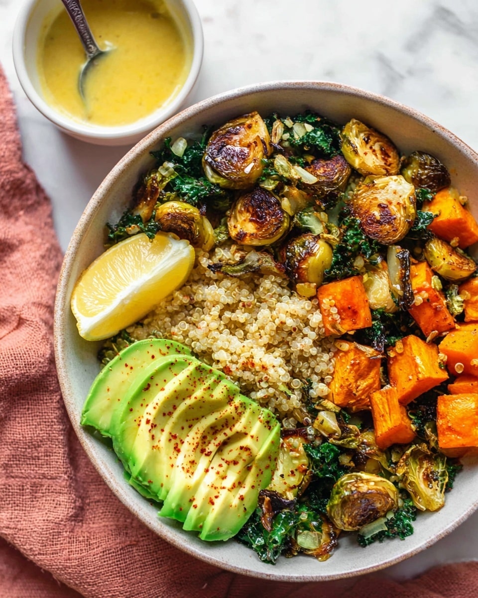 A white bowl filled with a colorful layered dish sits on a white marbled surface with a pink cloth nearby. The bottom layer is fluffy light beige quinoa with small round grains. On top, there are uneven pieces of roasted Brussels sprouts, showing a crispy brown exterior and green insides, mixed with fresh dark green kale leaves. Next to them, bright orange cubed roasted sweet potatoes with browned edges are scattered. Thin slices of pale green avocado with soft texture are arranged on one side, sprinkled with dark red seasoning. A wedge of lemon peeks from the edge of the bowl. In the top left corner, a small white bowl holds a yellow dressing, accompanied by a silver spoon. photo taken with an iphone --ar 4:5 --v 7