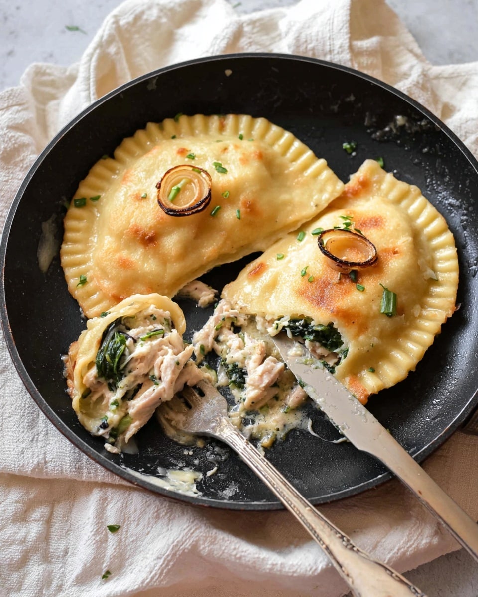 In a black skillet, two large pieces of cooked ravioli sit side by side, each with golden brown edges and slight crispiness on the surface. The top ravioli is whole with a few small, grilled onion rings and green herb pieces sprinkled lightly over it. The bottom ravioli is partially cut open, revealing a creamy filling layered with white ground meat and green spinach inside softly folded pasta. A silver fork is inserted into the cut ravioli, and a knife rests on the skillet edge with bits of filling on it. The skillet is placed on a crumpled light-colored cloth with a soft, white marbled texture in the background. Photo taken with an iphone --ar 4:5 --v 7