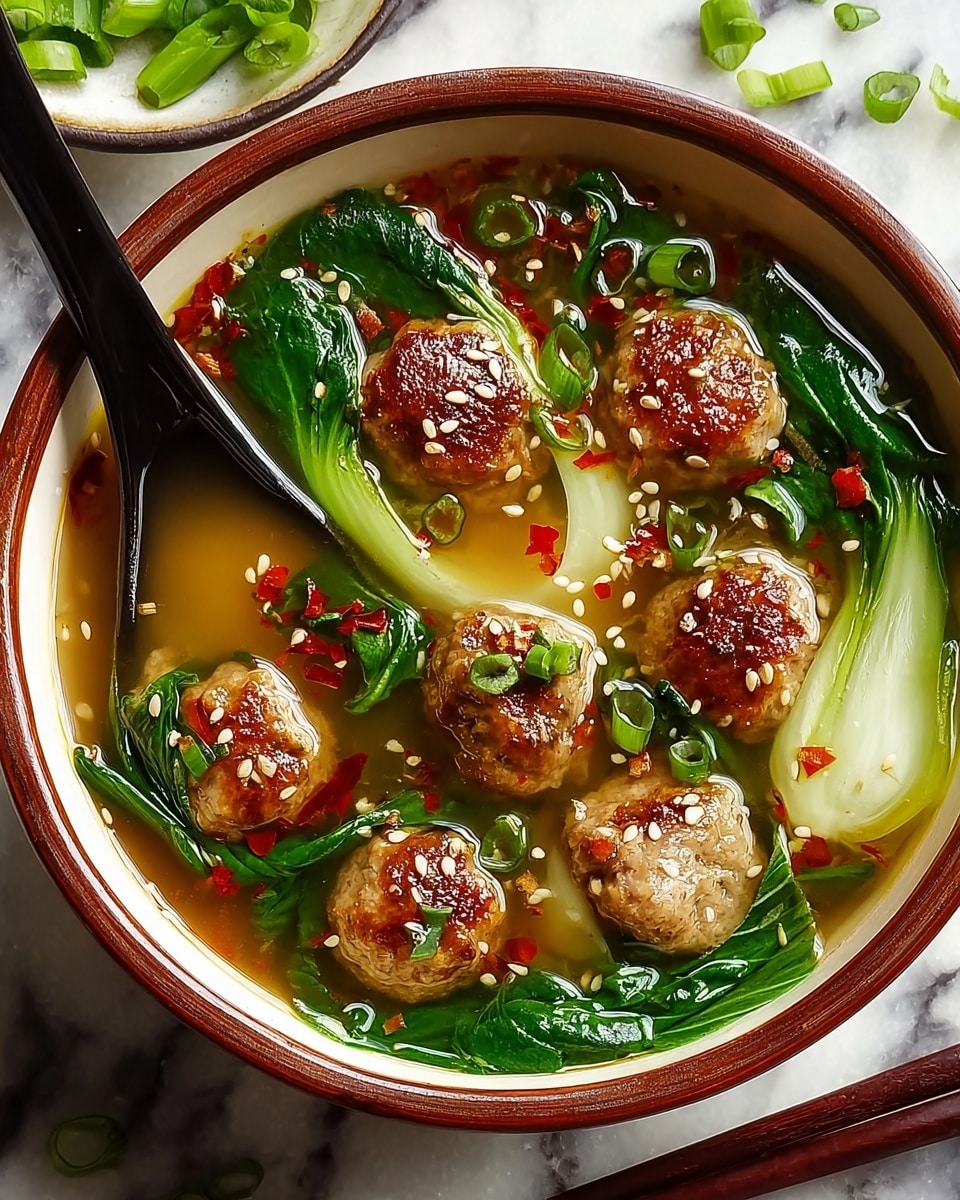 A white bowl with a brown rim holds a clear broth with a golden tint, floating seven browned meatballs arranged evenly inside. Bright green bok choy leaves with white stems sit beside the meatballs, partially submerged. Green onion slices and small red chili flakes scatter across the surface, along with white sesame seeds on top of the meatballs. A black spoon rests inside the bowl on the left side. The bowl is placed on a white marbled surface, with a pair of dark chopsticks on the right side. Photo taken with an iphone --ar 4:5 --v 7