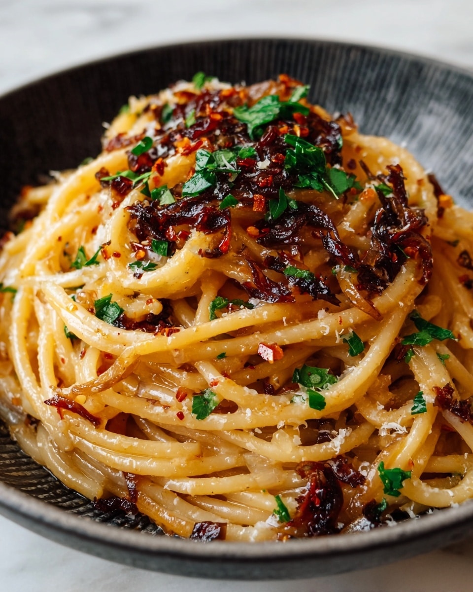 A close-up view of a plate of spaghetti with three layers visible: the bottom layer is thick, light golden pasta noodles, the middle layer consists of a mix of dark brown caramelized onions and red chili flakes scattered around, and the top layer is sprinkled with bright green chopped parsley and small shreds of grated cheese. The pasta looks glossy and slightly oily, served in a white plate with a textured black bowl inside, all set on a white marbled surface. photo taken with an iphone --ar 4:5 --v 7